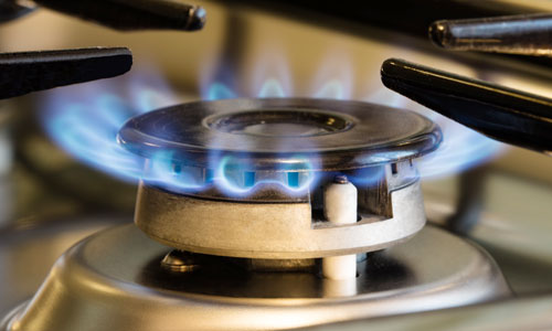 A gas stove with blue flames burning on top, fueled by natural gas