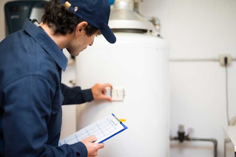 A plumber examining a water heater to ensure its proper functioning and identify any potential issues.