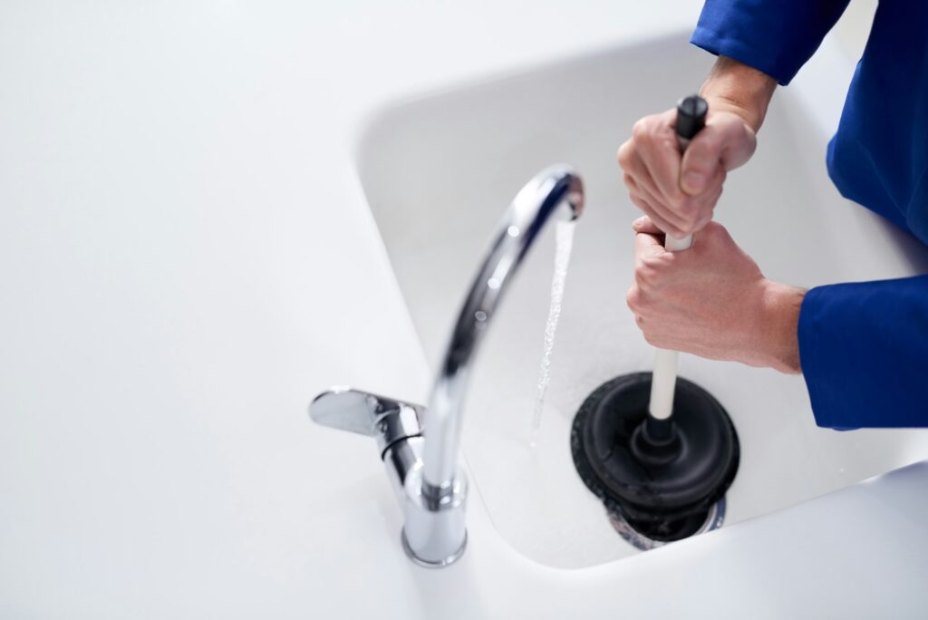 Keeping the drains clean. Cropped shot of a plumber unblocking a drain with a plunger.