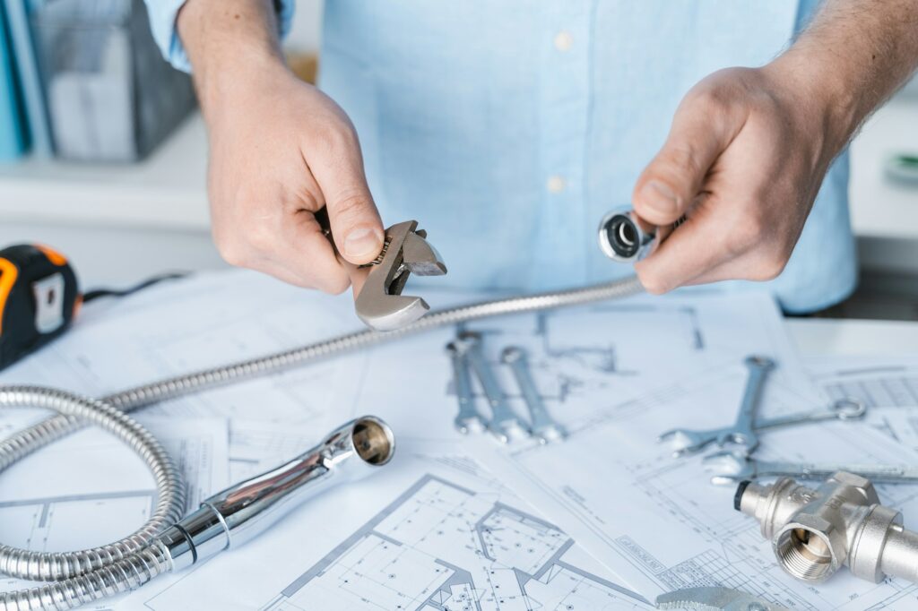 A man's hands gripping a wrench and plumbing tools tightly, ready for repair work.