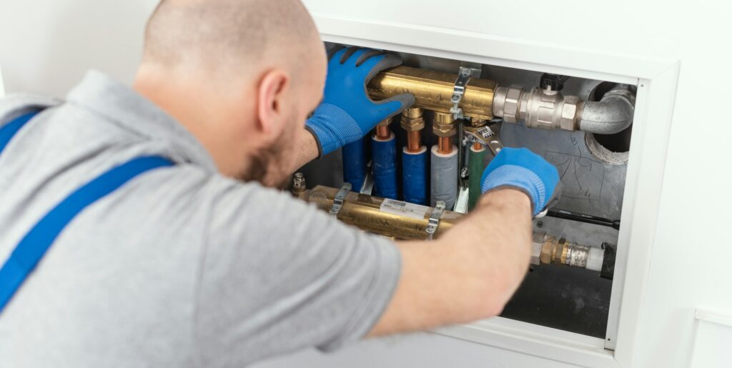 A man with blue shirt and gloves providing plumbing services.