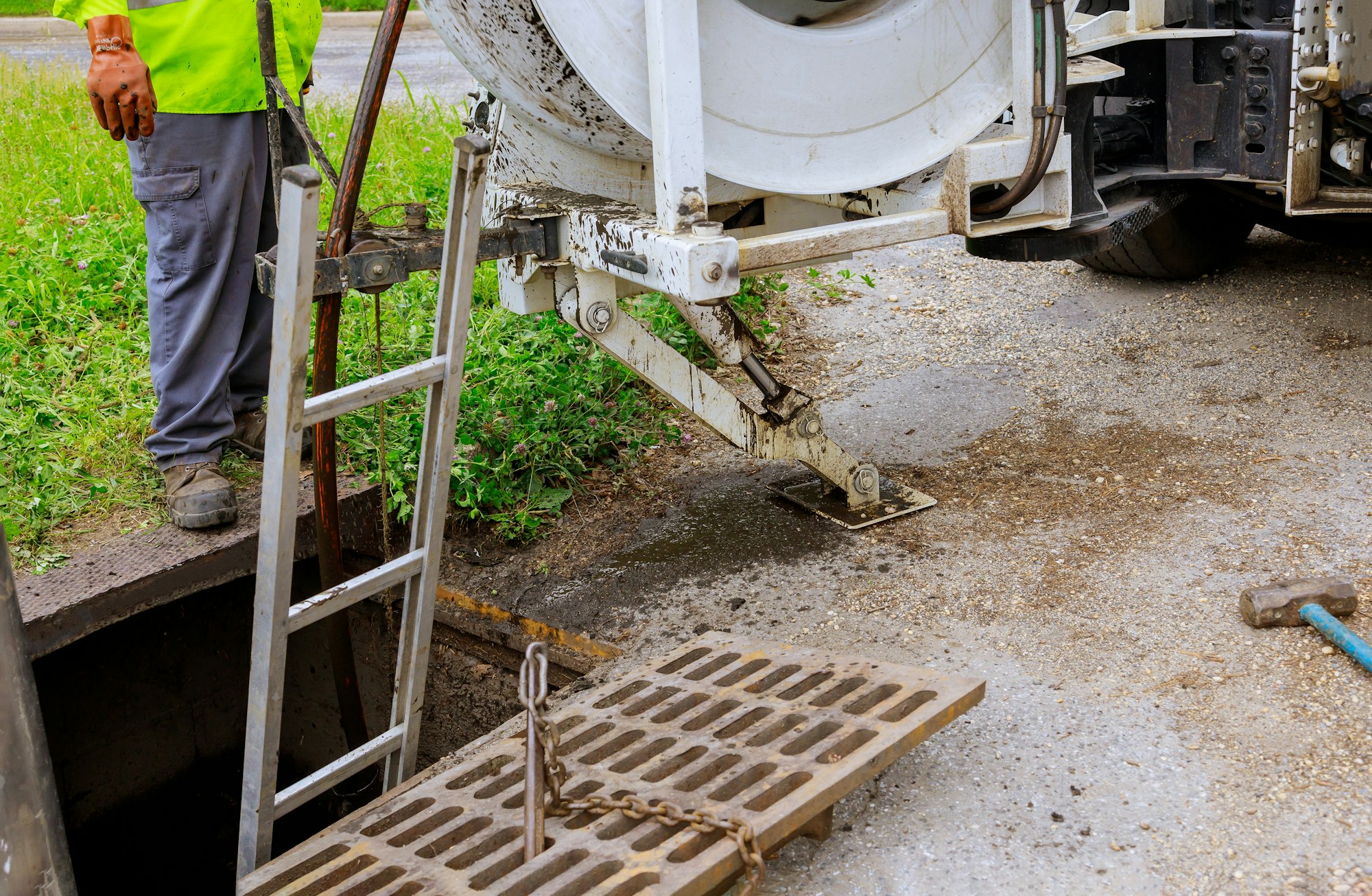 A man stands beside a sewer pipe, demonstrating plumbing work in a residential area.