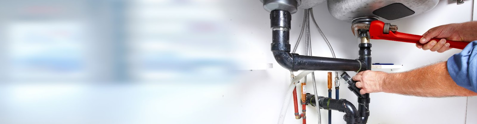 A man repairs a pipe with a wrench, showcasing skilled plumbing work in a residential construction setting.